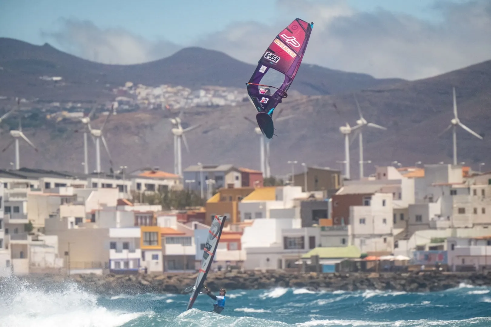 Windsurfista volando alto con el paisaje de Gran Canaria al fondo